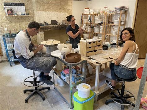 Photographie d'un atelier de poterie avec des participants travaillant sur des tours