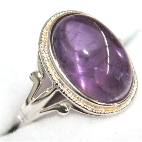 Gros plan sur une bague en argent sertie d'une améthyste verte aux reflets lumineux.