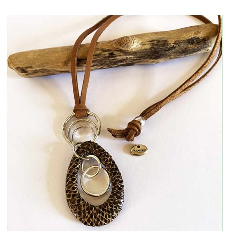 Gros plan d'un collier sautoir en cuir avec des boutons décoratifs, présenté sur un fond neutre.