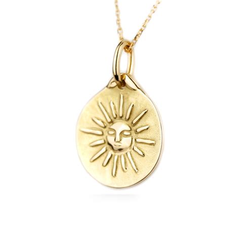 Détail d'un pendentif soleil en or jaune avec visage