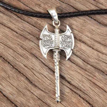 Gros plan sur un pendentif hache en argent massif avec des gravures de dragons