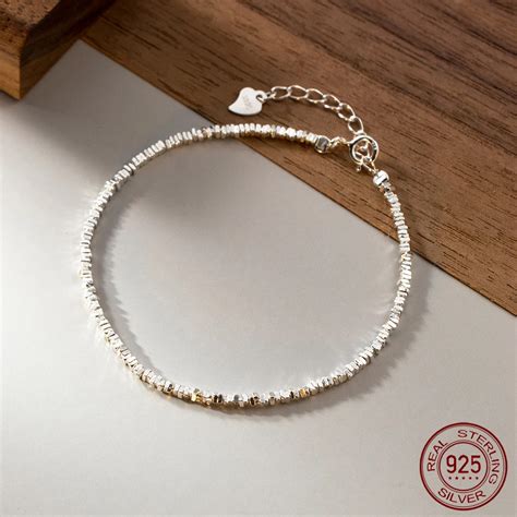 Une femme élégante portant un bracelet fin en argent sur son poignet.