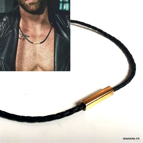 Homme portant un collier en cuir noir avec un pendentif discret.