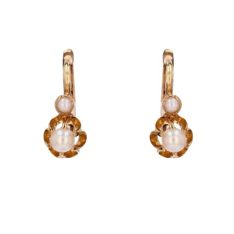 Une paire de boucles d'oreilles dormeuses élégantes ornées de perles et faites en argent.