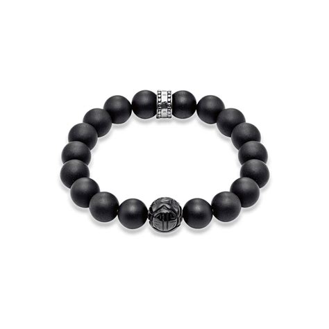 Gros plan sur un bracelet Thomas Sabo pour homme avec des perles de jaspe, une perle en argent et une obsidienne centrale.