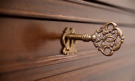 Détail d'une serrure ancienne avec sa clé sur une armoire Louis Philippe