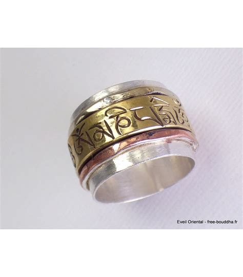 Gros plan sur une bague tournante tibétaine, mettant en évidence le mantra gravé et la perle centrale.