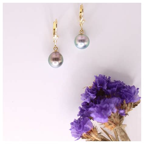 Vue rapprochée des boucles d'oreilles dormeuses avec perles de Tahiti grises et monture en or blanc