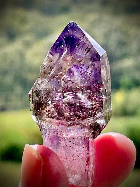Photographie d'une tourmaline rose aux inclusions internes ressemblant à de petits canaux