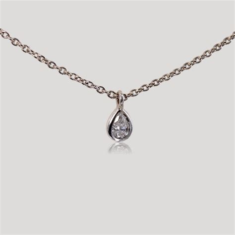 Gros plan sur un collier pendentif goutte de diamant avec des diamants sertis en halo