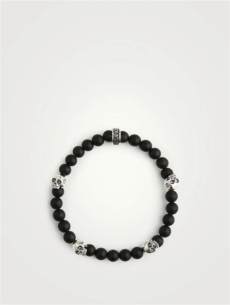 Vue d'ensemble du bracelet avec des crânes souriants en argent et un crâne central orné de zircons noirs