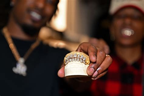 Photo de rappeur portant des grillz dorés ornés de diamants.