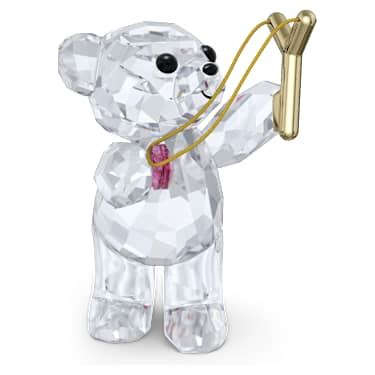 Figurine Ourson Kris de Swarovski lançant un cœur rose avec un lance-pierre.