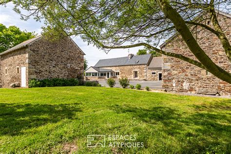 Extérieur de l'ancien corps de ferme rénové avec ses murs en pierre et poutres apparentes