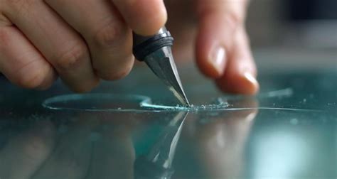 Photographie d'une main gravant délicatement un bijou avec un outil de joaillerie