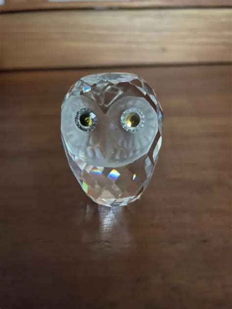 Illustration d'une figurine de bébé chouette Swarovski en cristal incolore avec des yeux jaunes et noirs.