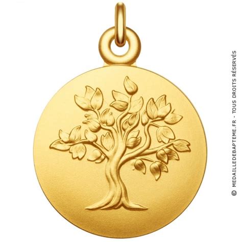Une main d'enfant tenant une médaille Arbre de Vie en or jaune 9 carats