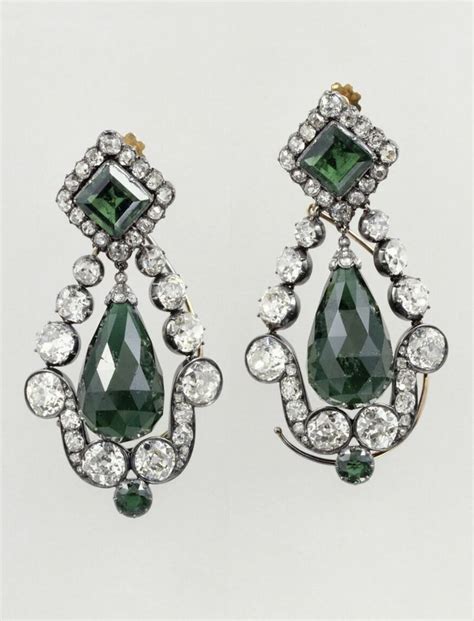 Une paire de boucles d'oreilles en or blanc avec un grenat central et de petits diamants incrustés sur le contour, dans un style sophistiqué.