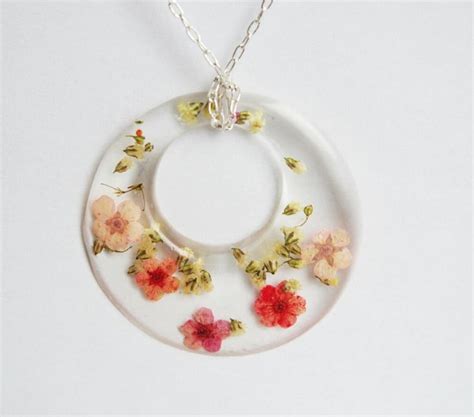 Collier rond doré avec des fleurs séchées roses capturées dans de la résine époxy transparente