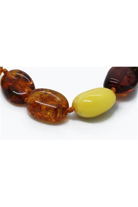 Grosses perles d'ambre aux couleurs variées (jaune, cognac, cerise) formant un collier élégant.