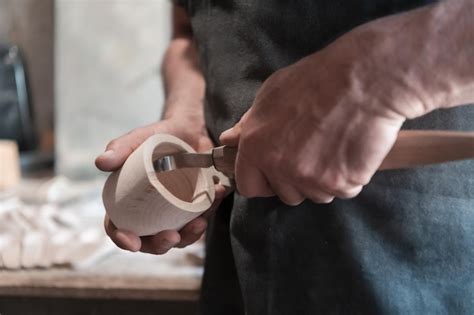 Gros plan sur des mains d'artisan découpant avec précision un éclat d'assiette ancienne.
