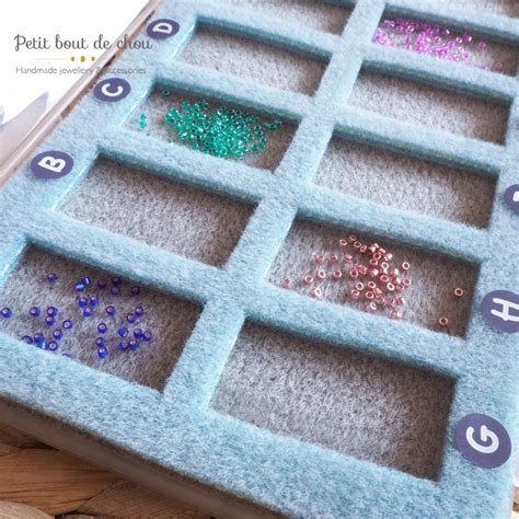 Photo de différents accessoires pour le tissage de perles : tapis de perlage, aiguilles, fils, ciseaux, fermoirs.