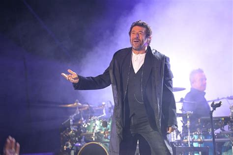 Patrick Bruel sur scène, interagissant avec le public dans une ambiance festive à l'Espace Carat.