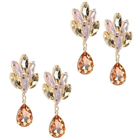 Boucles d'oreilles pendantes en forme de fleur rose avec des détails dorés, portées par un mannequin pour illustrer le style.