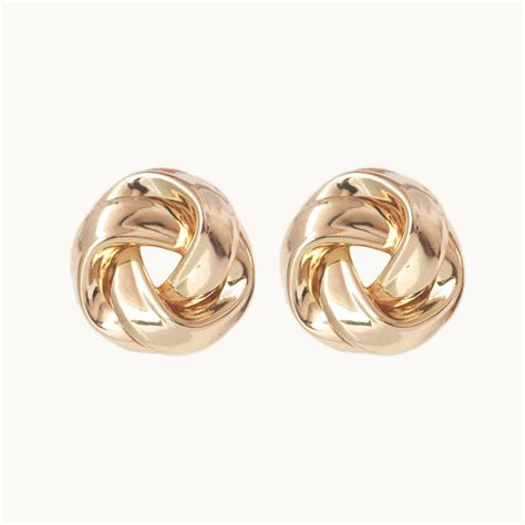 Gros plan sur une boucle d'oreille ronde en argent ornée d'une marqueterie de paille rose poudré et de porcelaine blanche.