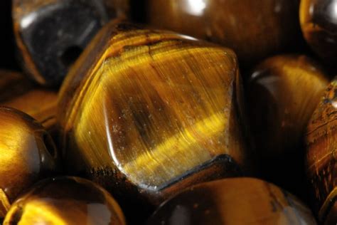 Vue rapprochée d'une pierre d'œil de tigre, mettant en évidence ses reflets chatoyants et ses bandes brun doré et jaunes.