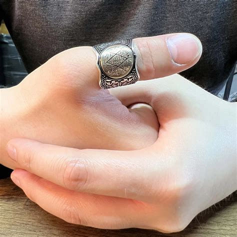 Homme portant une bague au pouce, symbolisant l'audace et l'individualité.