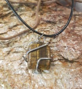 Photographie d'un pendentif œil de tigre pour homme, en forme de dent, sur un cordon en nylon.