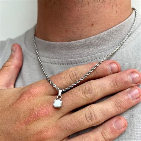 Homme portant une chaîne en argent avec un pendentif discret.