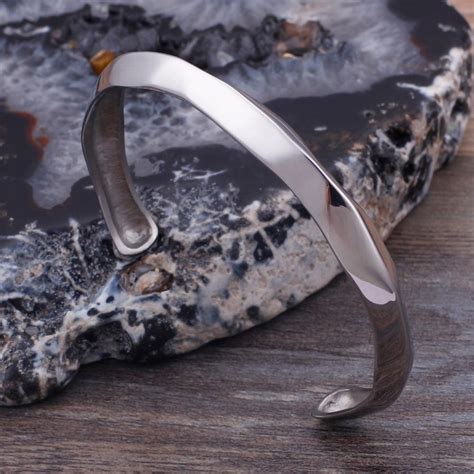 Gros plan sur la texture et la finition d'un bracelet jonc en argent, soulignant la qualité du métal.