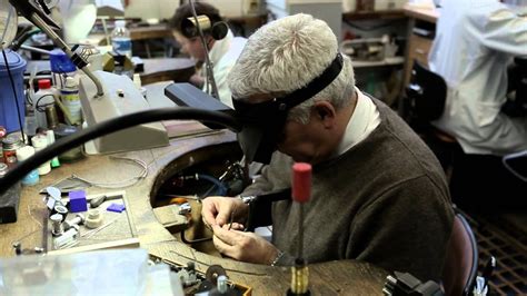 Gros plan sur un artisan joaillier travaillant avec précision sur une médaille de bracelet pour enfant.
