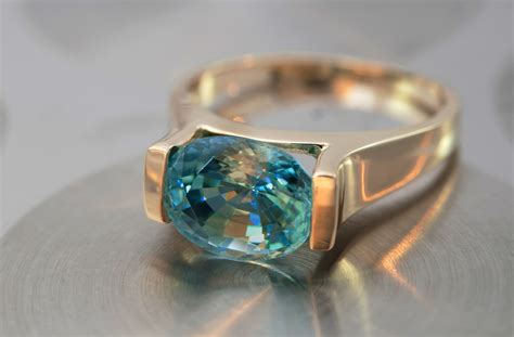 Gros plan sur une bague homme avec une aigue-marine taillée en coussin, mise en valeur par une monture en or blanc.