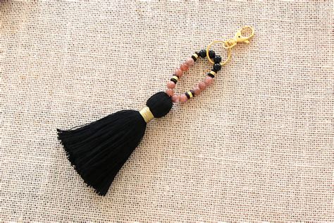 Porte-clés décoratif avec des perles gemmes, un pompon coloré et des breloques fines.