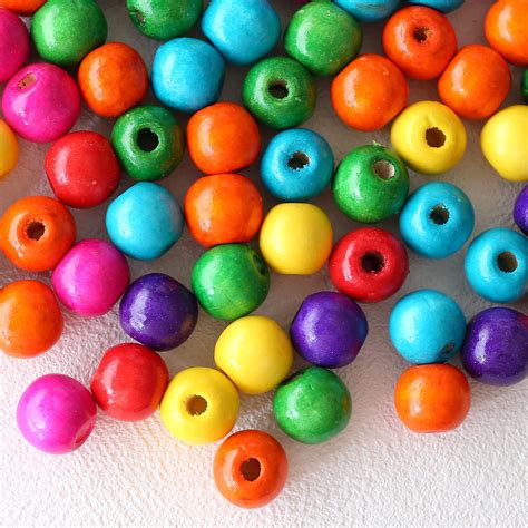 Gros plan sur des perles en bois colorées de différentes tailles, prêtes à être utilisées pour la création de bijoux.