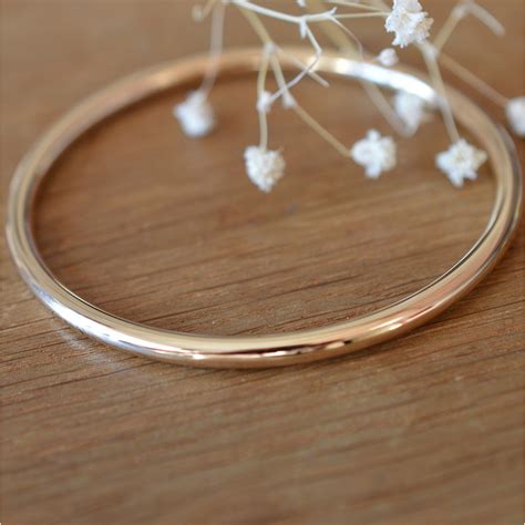 Gros plan sur la texture d'un bracelet jonc plaqué or, mettant en évidence la finition.