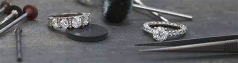 Photographie de Bernard Sylvain souriant, entouré d'outils de joaillerie