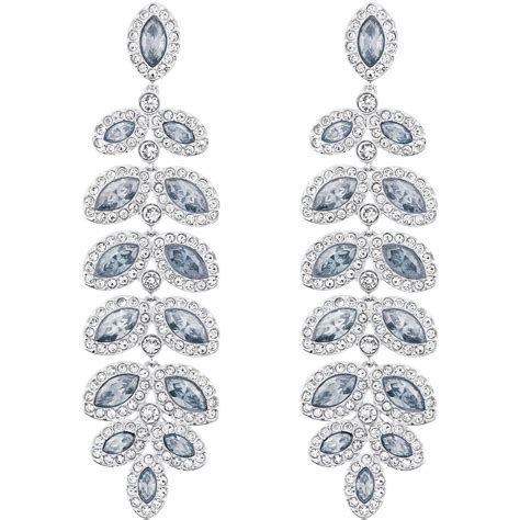 Photographie d'une femme portant des boucles d'oreilles Swarovski pendantes lors d'une soirée, avec une tenue élégante.