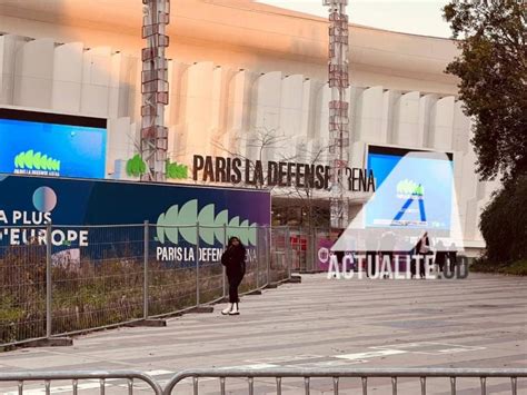 Photo de fans attendant l'ouverture des portes d'une salle de concert, brandissant des affiches.