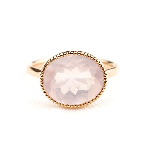 Photographie d'une bague fine avec un quartz rose central et un anneau en or jaune