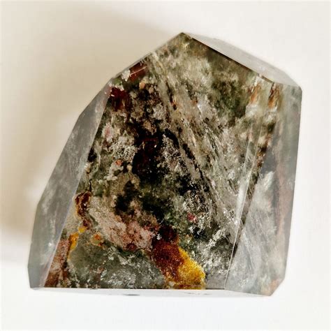 Photographie d'un quartz lodolite aux inclusions complexes ressemblant à un paysage miniature.