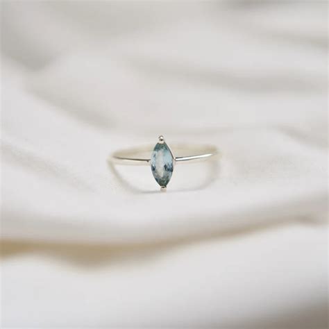 Photographie d'une aigue-marine aux reflets bleus translucides et d'une bague sertie d'aigue-marine.