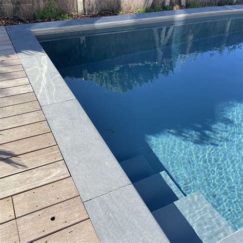 Photographie d'une piscine avec margelles en Pierre Bleue du Hainaut, mettant en avant sa résistance à l'eau et son aspect esthétique.