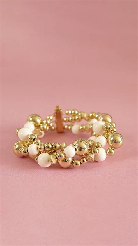 Gros bracelet composé de perles dorées et crème avec un fermoir multirang