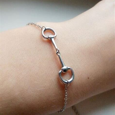 Gros plan sur un bracelet mors de cheval en argent, mettant en valeur les détails de la finition.