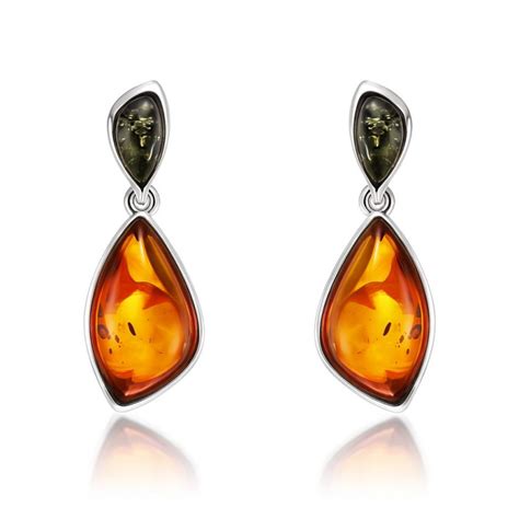 Une femme portant des boucles d'oreilles pendantes en ambre, mettant en valeur leur mouvement et leur couleur.