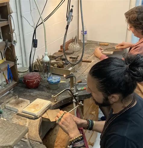 Atelier de fabrication de bijoux, artisan travaillant le métal avec des outils spécifiques.